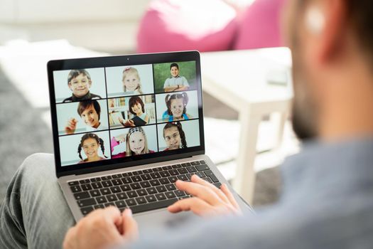 Male teacher having online conference with school children working at home