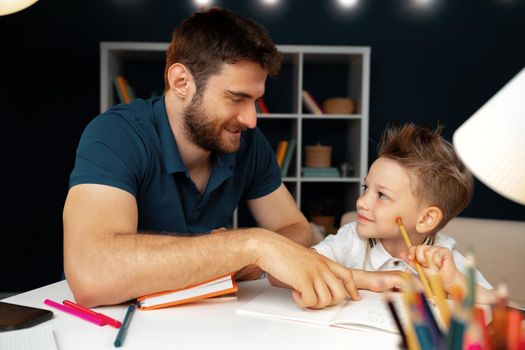Father helping his little son with school homework close up