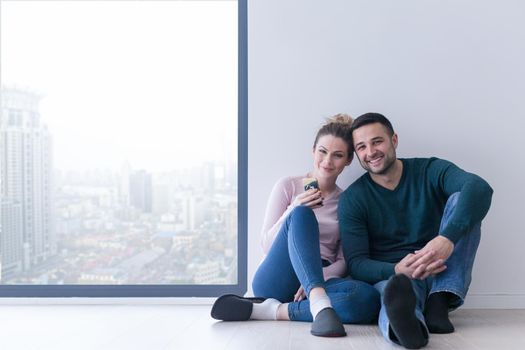 happy young couple sitting near window at home on cold winter day