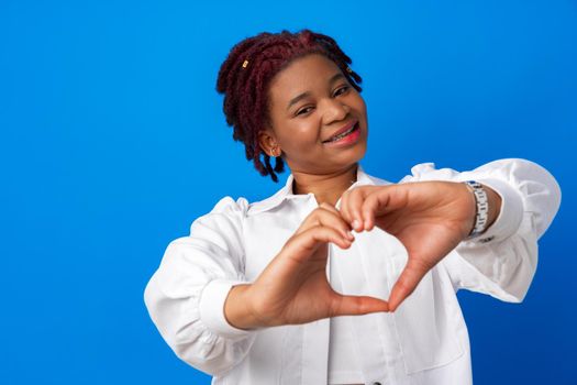 Nice afro woman put hands in heart shape against blue background, close up