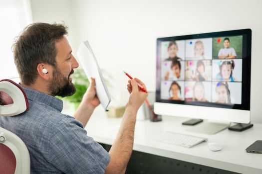 Male teacher having online conference with school children working at home