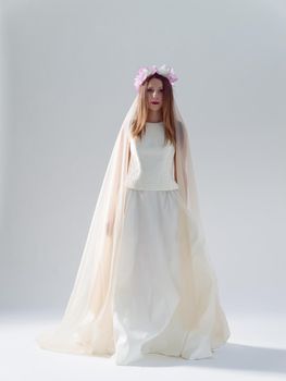 Portrait of beautiful young bride in a wedding dress with a veil isolated on a white background