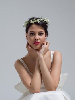 Beautiful young bride sitting in a wedding dress isolated on a white background