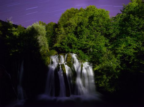 beautiful waterfall with clear drinking water and  stars trails on night sky