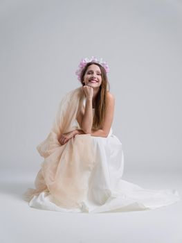 Beautiful young bride sitting in a wedding dress isolated on a white background