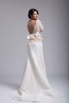 Rear view of a beautiful young bride in a wedding dress isolated on a white background