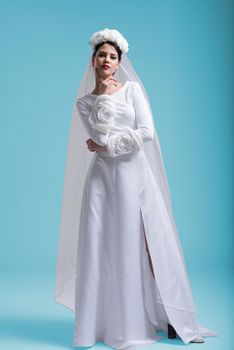 portrait of beautiful young woman as bride in wedding dress isolated on cyan backgrond in studio