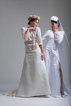 Portrait of two beautiful young bride in wedding dresses isolated on a white background