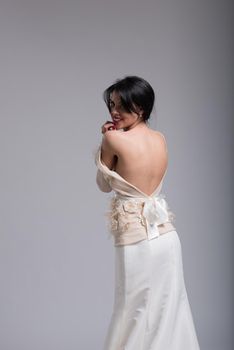 Rear view of a beautiful young bride in a wedding dress isolated on a white background