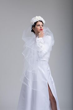 Portrait of beautiful young bride in a wedding dress with a veil isolated on a white background