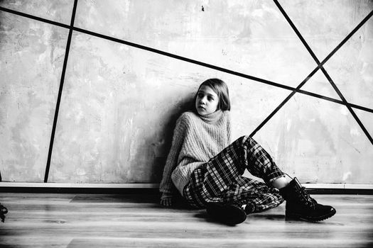 cute teen girl sitting near the wall. photo with copy space. black and white photo