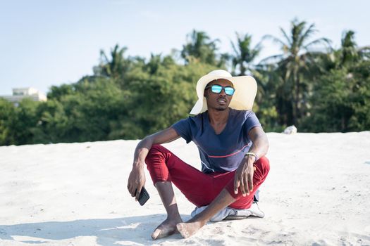 African man sitting on sandy beach