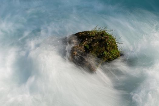 single stone in wild river landscape  long exposure photo representing liquid flow concept