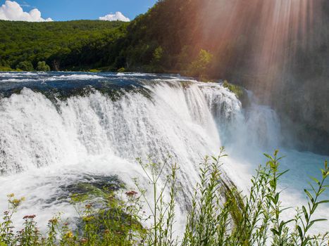 waterfall in beautiful nature with crystal clear water on wild river una in bosnia and herzegovina at sunny summer day