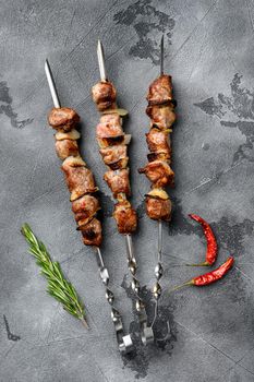 Juicy skewers of pork meat or shashlik set, on gray stone table background, top view flat lay