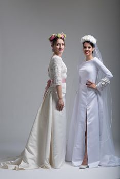 Portrait of two beautiful young bride in wedding dresses isolated on a white background