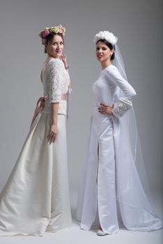 Portrait of two beautiful young bride in wedding dresses isolated on a white background