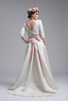 Rear view of a beautiful young bride in a wedding dress isolated on a white background