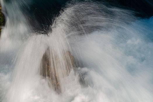 single stone in wild river landscape  long exposure photo representing liquid flow concept