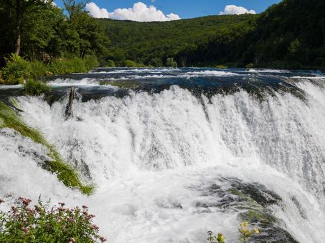 waterfall in beautiful nature with crystal clear water on wild river una in bosnia and herzegovina at sunny summer day