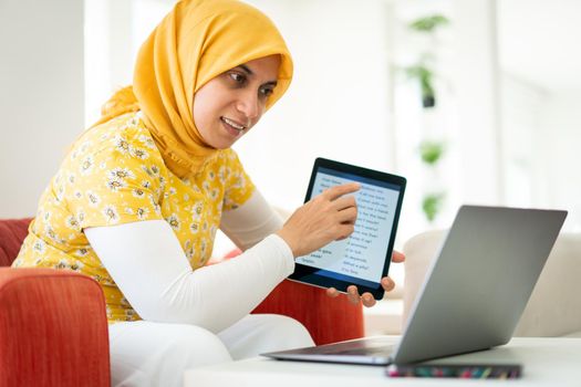 Muslim woman teaching on tablet at home today