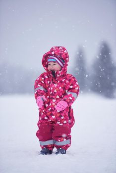 happy family on winter vacation, mom and cute little girl have fun and slide while snow falkes falling