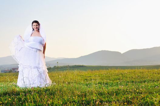 happy young beautiful bride after wedding ceremony event have fun on meadow in fashionable wedding dress