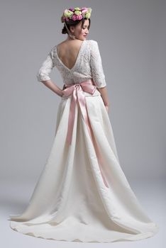 Rear view of a beautiful young bride in a wedding dress isolated on a white background