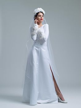 Portrait of beautiful young bride in a wedding dress with a veil isolated on a white background