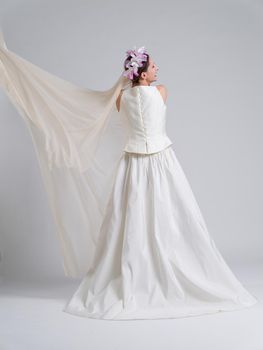 Rear view of a beautiful young bride in a wedding dress isolated on a white background