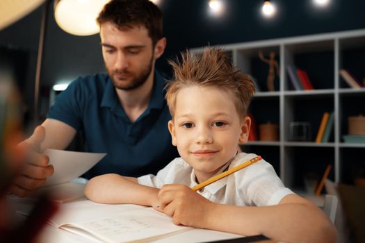 Dad and son doing school homework together sitting at the table