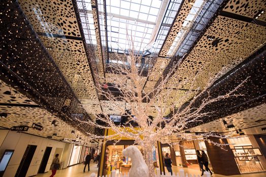 Glowing white tree made of wire and light bulbs in big modern shopping mall