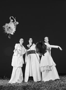 group of bride run on meadow at sunset after wedding party