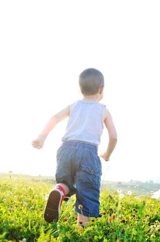 little happy child play with windmil toy and have ve fun while running on beautiful meadow at sunset