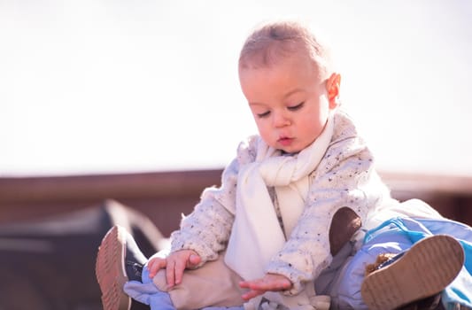 portrait of cute little baby boy sitting on table during beautiful winter day outside