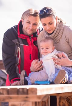 portrait of young happy family with little child enjoying beautiful winter day outdoors
