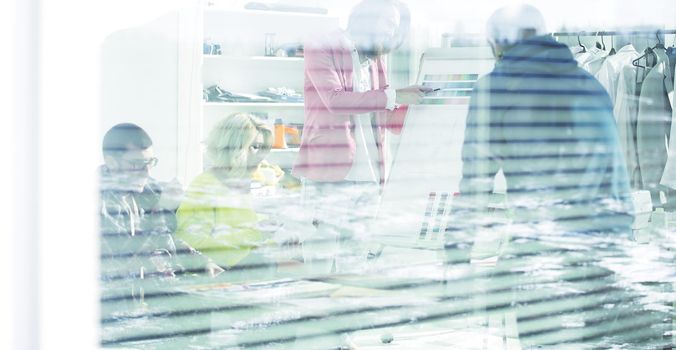 View through the blinds. a group of fashion designers in a modern Studio.