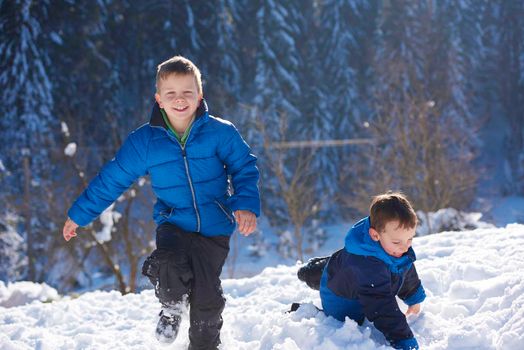 happy kids playing in fresh snow at beautiful  sunny winter day