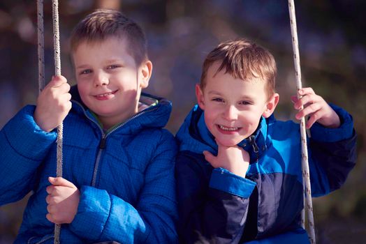 portrait of two little boys with slides  in nature at beautiful sunny winter day with fresh snow