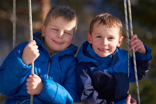 portrait of two little boys with slides  in nature at beautiful sunny winter day with fresh snow