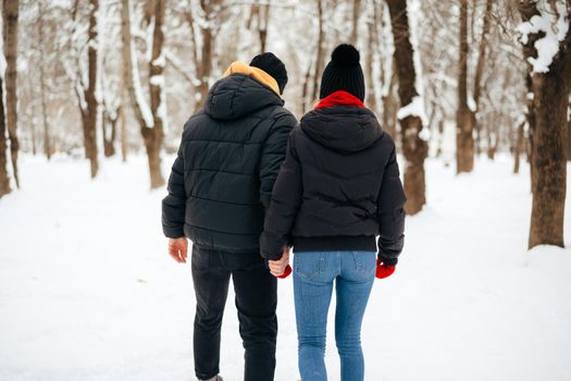 Young happy smiling couple in love having a walk in a winter park