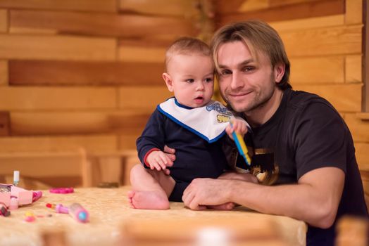 Father and son happy moments  Portrait of young father and his cute baby son playing together on table while spending time together at home