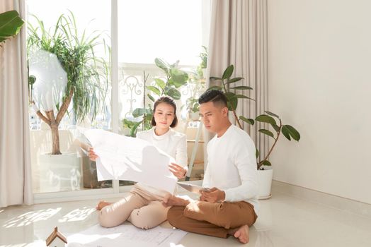 Young couple looking at blueprints of new home