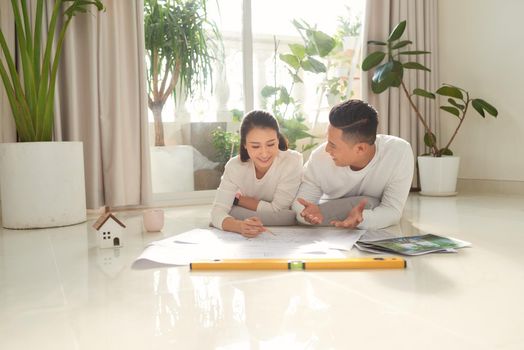 Young couple sitting on floor with apartment plan