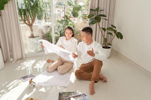 Young couple sitting on floor with apartment plan