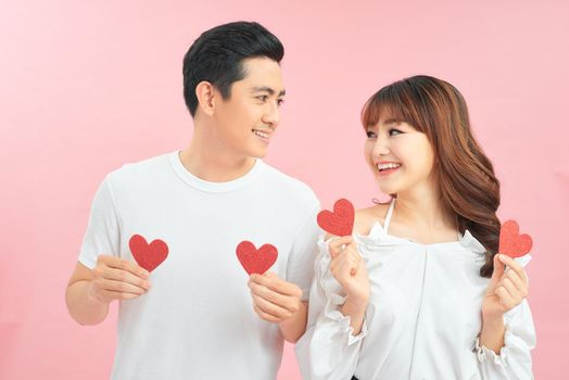 Two lovers holding paper heart on pink background