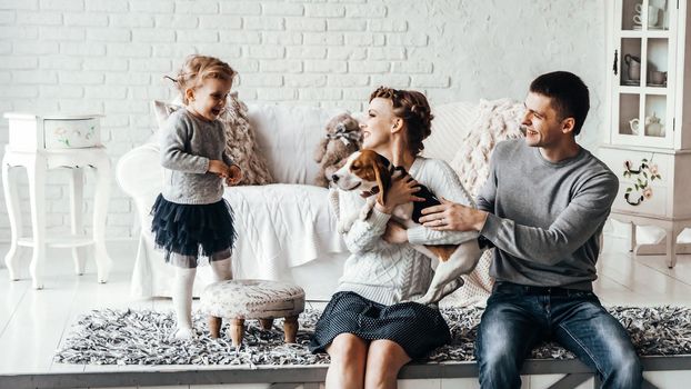 happy parents with five-year-old daughter and their pet dog in the cosy living room