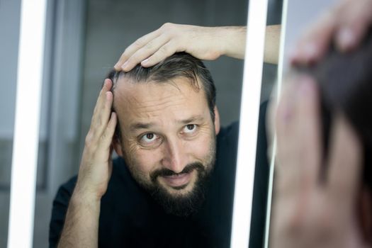 Man in front of mirror checking hair and skin