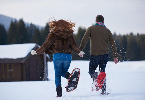 happy young  couple having fun and walking in snow shoes. Romantic winter relaxation scene