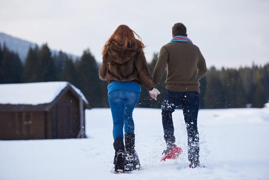 happy young  couple having fun and walking in snow shoes. Romantic winter relaxation scene